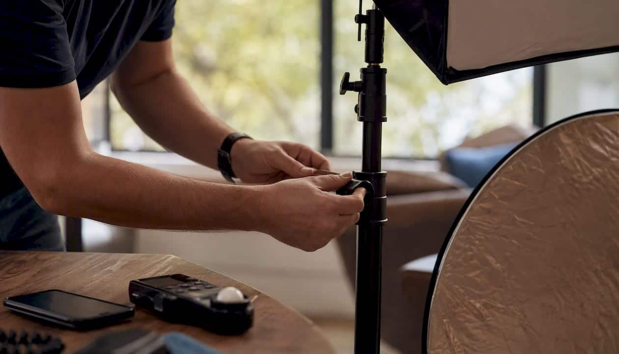 Des mains règlent les paramètres d’éclairage dans un studio.