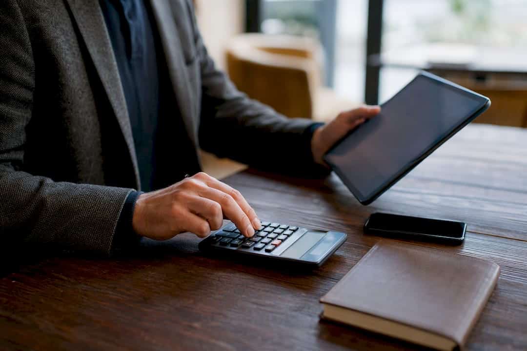 Mains calculant le coût de l'assurance au bureau avec une tablette
